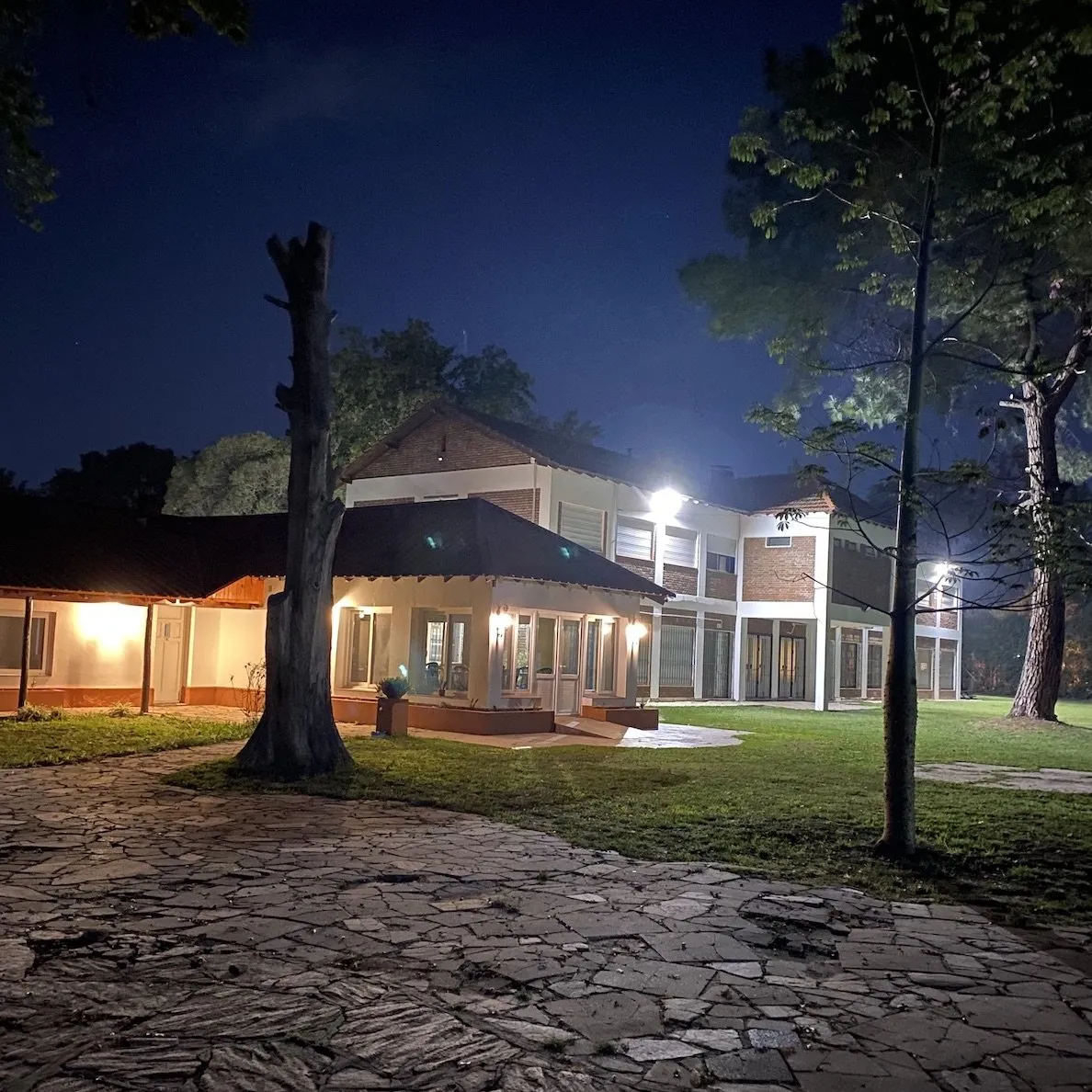 The retreat venue building illuminated at night with warm lighting and stone pathways
