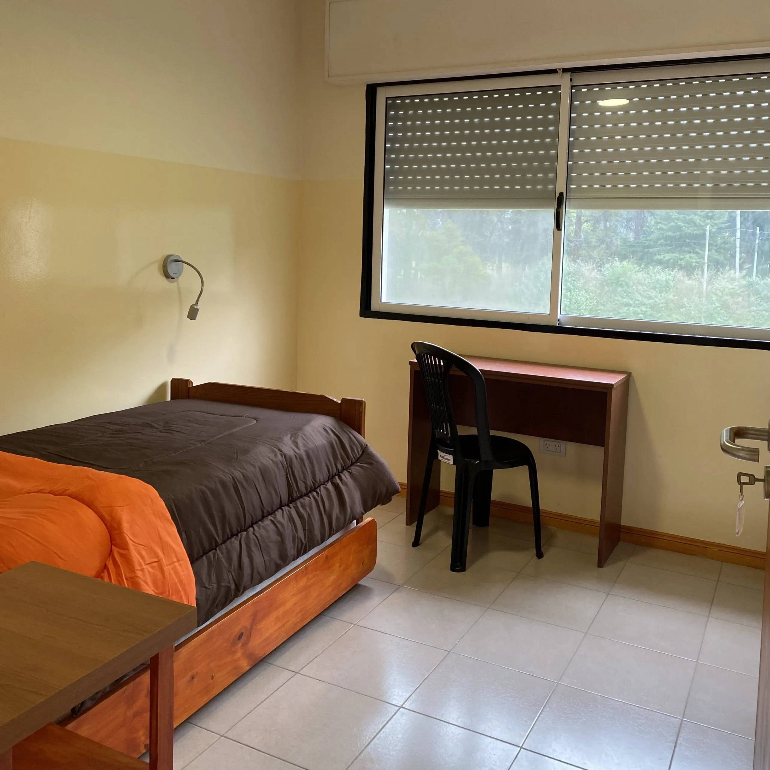 Private retreat bedroom with bed, study desk, and window overlooking the grounds